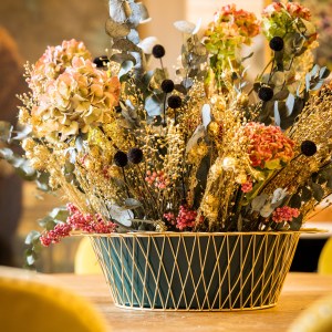 Forest green planter with a gold wire mesh arranged with Christmas flowers