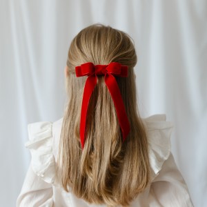 Girl showing her red velvet hair bow in a white blouse
